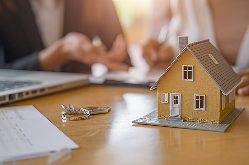Property model, keys, and paperwork on a desk during a property consultation